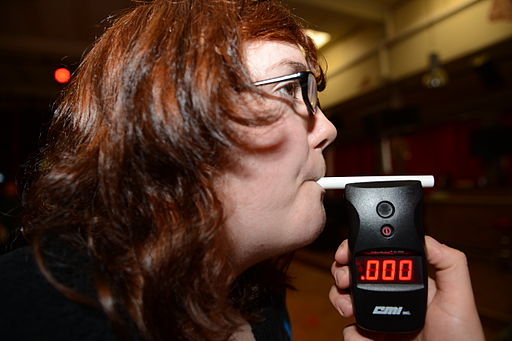 Red head woman blowing into a breathalyzer